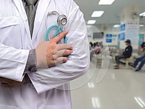 Doctor in gown uniform with stethoscope standing and fold his arms over the chest on OPD background