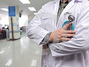 Doctor in gown uniform with stethoscope standing and fold his arms over the chest on OPD background