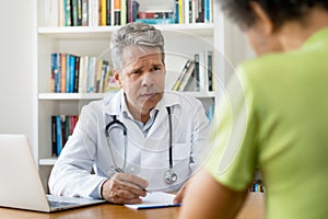 Doctor with gray hair listening to patient