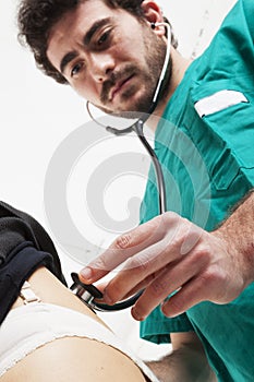 Doctor with green uniform do back auscultation with stethoscope. photo
