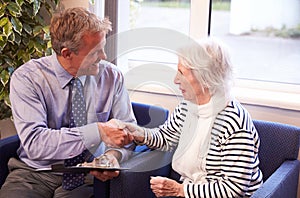 Doctor Greeting Senior Female Patient With Handshake