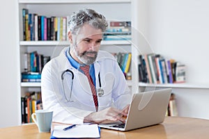 Doctor with grey hair working with computer