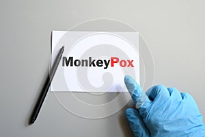 Doctor hand in blue glove with pen indicate Monkeypox words on white paper. Monkeypox on white paper. Monkeypox virus concept photo