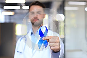 Doctor hand with blue prostate cancer awareness ribbon. Medicine oncology closeup sky symbol