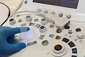 Doctor hand in blue sterile glove moving blue backlit trackball on moden diagnostic ultrasound machine