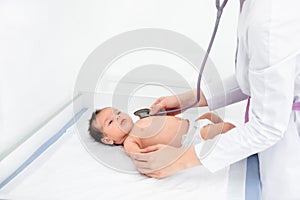Doctor hand hold tiny Asian newborn baby sick sleeping during examine by pediatrician doctor with stethoscope, doctor monitoring