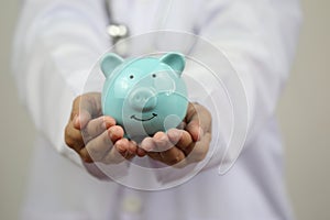 Doctor hand holding blue piggy bank on white background, Health insurance concept