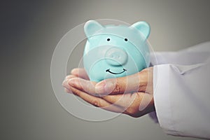 Doctor hand holding blue piggy bank on white background, Health insurance concept