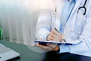 Doctor hand holding pen writing patient history list on clipboard about medication and treatment