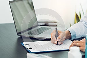 Doctor hand holding pen writing patient history list on clipboard about medication and treatment