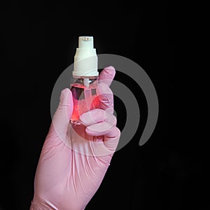 Doctor hand holding a sanitizer on a black background, close-up. Nurse with hand hygiene product. Concept of disinfection in
