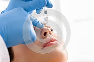 Doctor hand injecting in face of calm woman