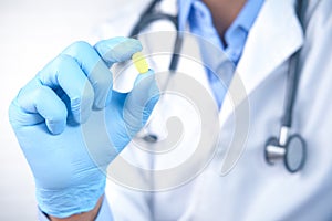 doctor hand in latex gloves holding medical pill close up