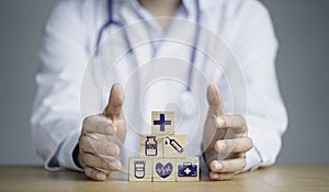 Doctor hand protect wooden stacking with healthcare medical and hospital icons on table , Health and insurance concept