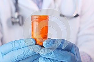 Doctor hand in protective glass holding pill container