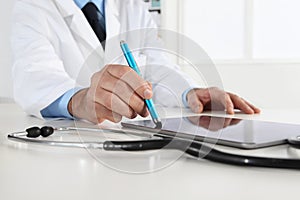 Doctor hand touch screen of digital tablet writing prescription at desk in medical office close up