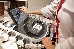 Doctor hands on control panel with keyboard of medical ultrasound diagnostic equipment in clinic