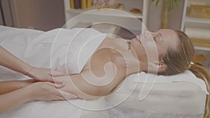 Doctor hands do massage shoulder and hand of young woman in spa salon.