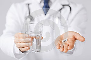 Doctor hands giving white pills and glass of water