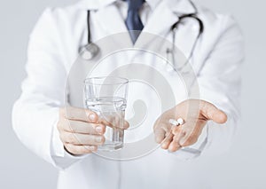 Doctor hands giving white pills and glass of water