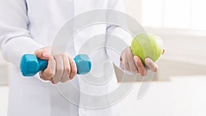 Doctor hands with green apple and dumbbell