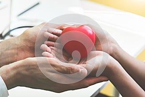 Doctor hands holding and giving red massage heart to patient little children for recover from sickness. Hospital and Healthcare