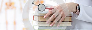 Doctor hands are holding stack of books and stethoscope