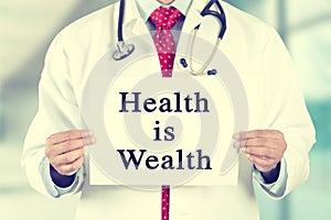 Doctor hands holding white card sign with health is wealth text message