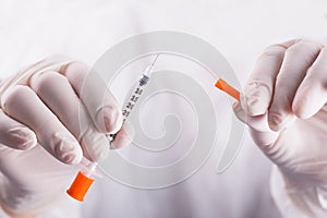 Doctor hands in rubber gloves holding open insulin syringe on white background