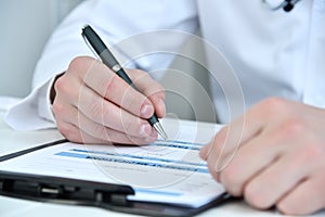 Doctor hands writing on clipboard in medical office