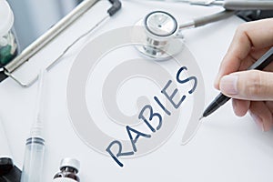 Doctor hands writing Rabies disease on the paper photo