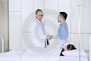 Doctor handshaking with father patient in hospital