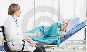 A doctor happily talks with a patient lying in bed