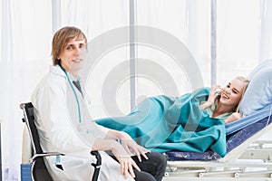 A doctor happily talks with a patient lying in bed