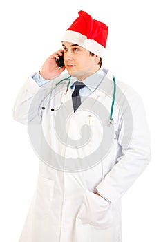 Doctor in hat of Santa Claus talking on mobile
