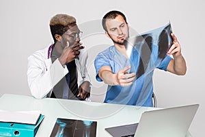 Doctor having conversation with his colleague and holding xray in medical office. Medical office