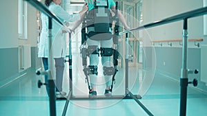 Doctor is helping a disabled man in the exoskeleton