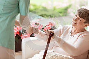 Doctor helping an elderly woman with Parkinson`s disease get up