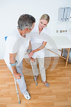 Doctor helping her patient walking with crutch