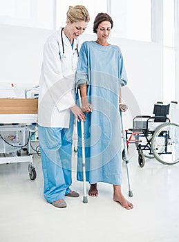 Doctor helping patient in crutches at the hospital