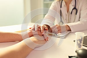 Doctor with his hand calming patient in clinic closeup