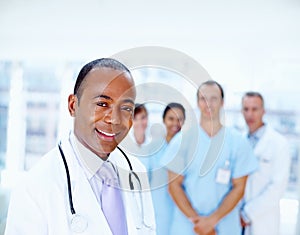 Doctor with his staff. Focus on doctor with team in background.