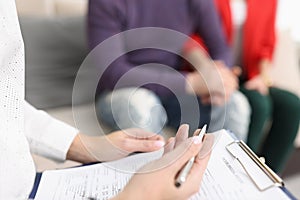 Doctor hold clipboard with patient medical history paper for couple