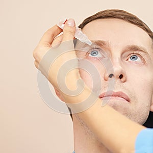 Doctor hold eye drops near patient face