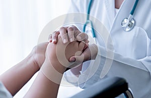 doctor hold hands patient Which sat on wheelchair to encourage