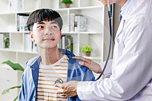 Doctor hold stethoscope listen to teenager boy patient heart in