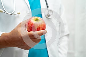 Doctor holding apple fruit vitamin food for healthy patient in hospital