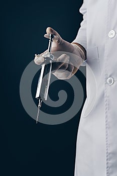 Doctor holding a big stainless steel syringe