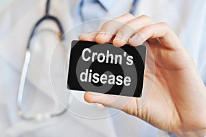 Doctor holding a paper card with text Crohn`s disease, medical concept photo