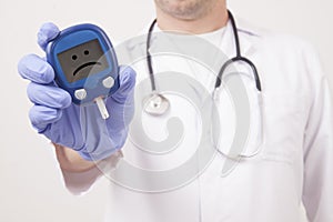 Doctor holding blood sugar meter. Sad smiley face